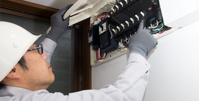 An electrician repairing an electrical board wearing safety conductive gloves.