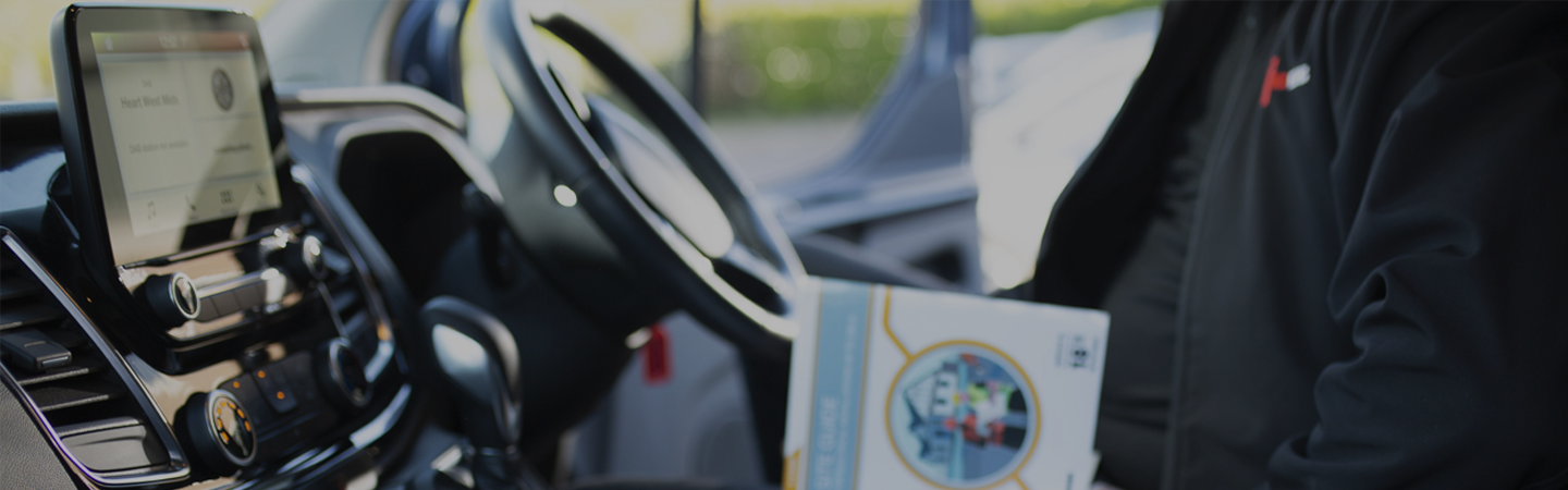 An NICEIC approved contractor sitting in a parked vehicle, reading the winter 2022 2023 edition of the connections magazine.