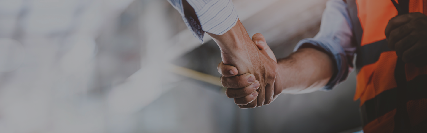 construction worker wearing a hi-viz jacket shaking hands with man in shirt