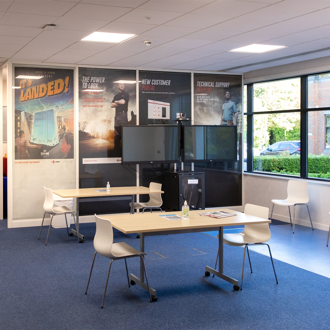 NICEIC Training room waiting area. White tables and chairs with a double TV