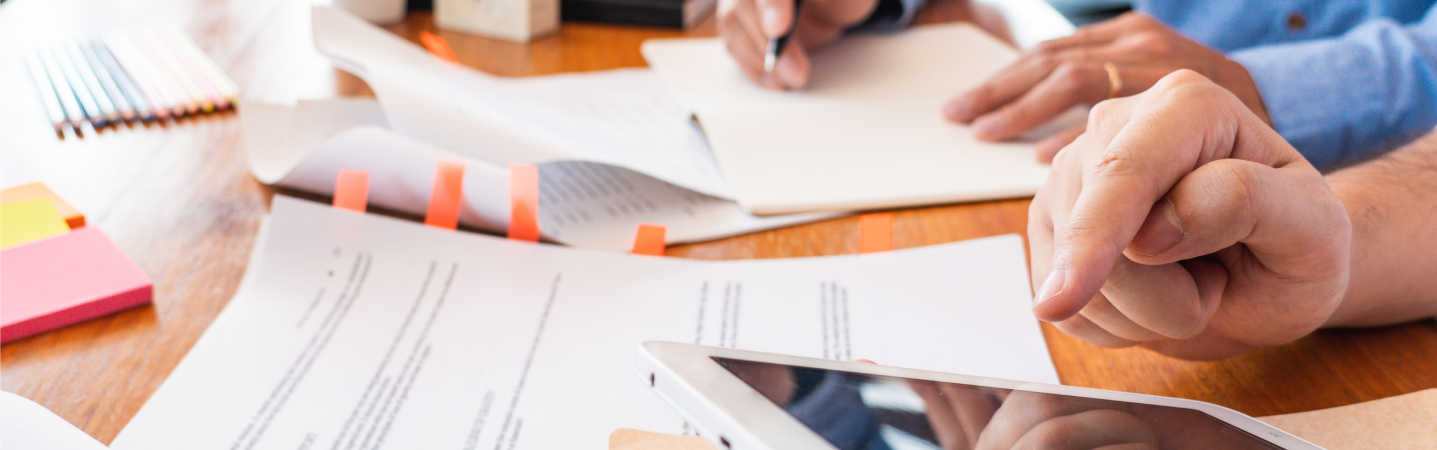 Two people looking over paperwork with an electronic tablet